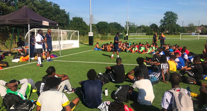 Imber Metz football players sat on a pitch listening to their trainer.