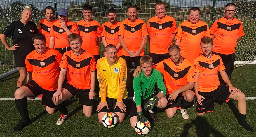 Swale Tigers team pose in their new orange football kit.