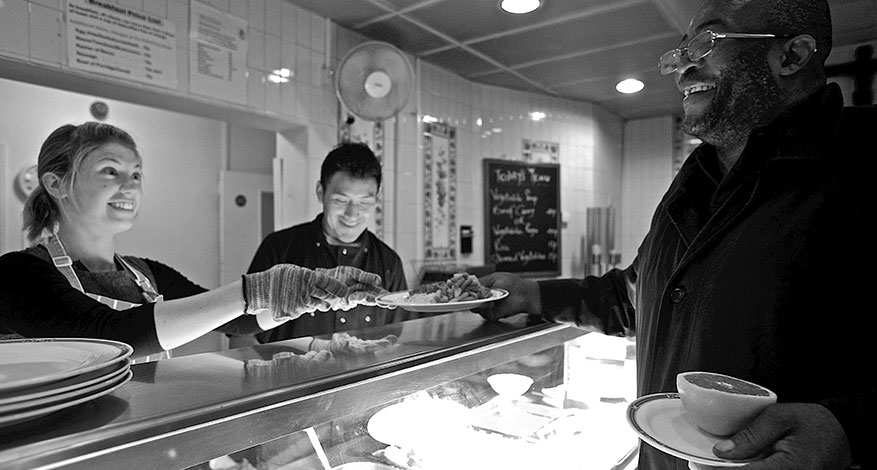 Homeless man being served food in The Passage homeless kitchen.