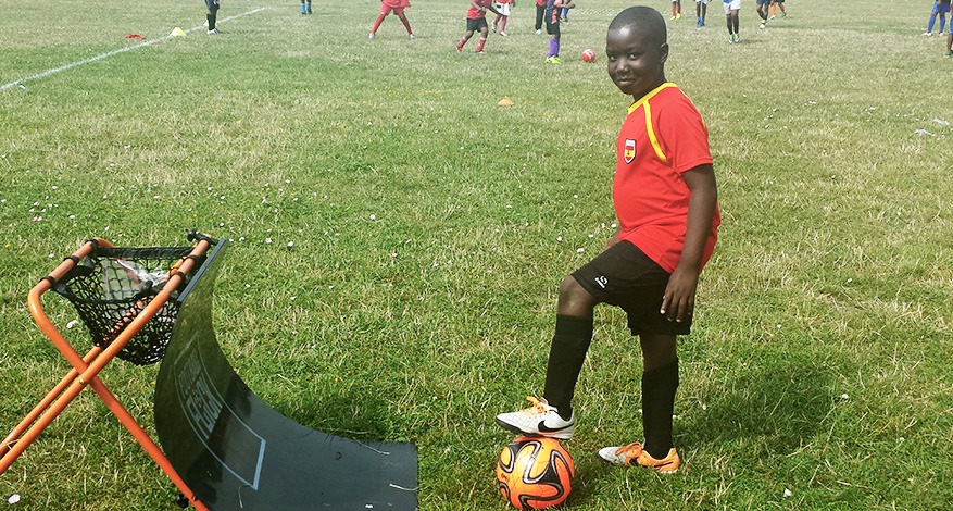 Boy stands on ball next to new sports equipment at Confidence through sport