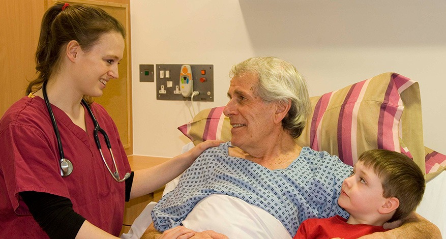 Woman carer standing next to elderly man and child at St Johns Hospice