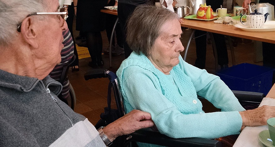 Elderly Woman at daycare centre being supported by unpaid carer