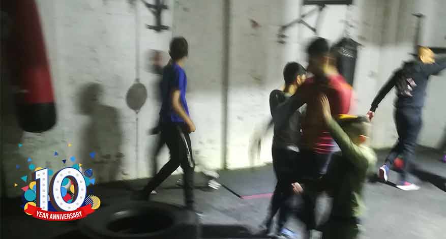 young people in boxing gym with tyre plus 10th anniversary logo