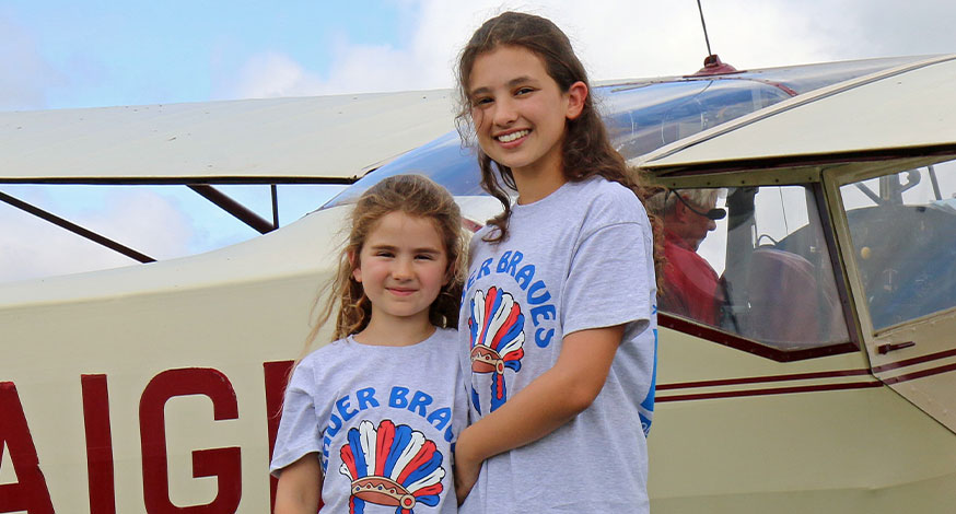 Two young girls stood next to plane at bader braves young aviator day