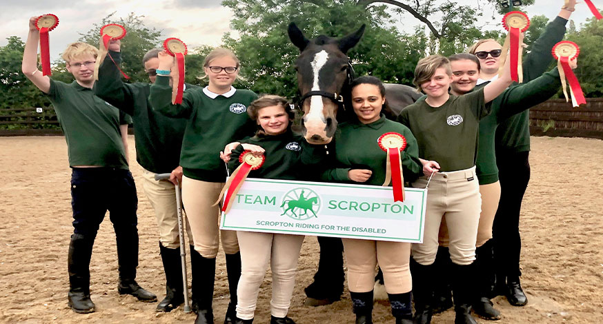 Riders at Scropton Riding for the Disabled with rosettes and a horse