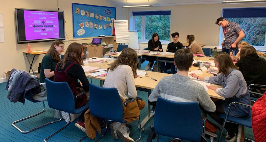 Students sitting at tables studying to become Mental Health Ambassadors