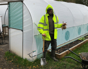 Man and wheelbarrow standing in front of polytunnel