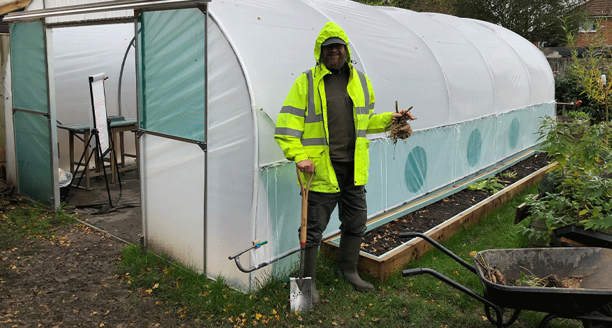 Man and wheelbarrow standing in front of polytunnel