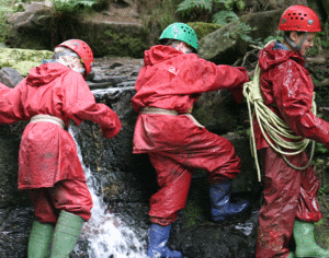 Children in Wellingtons on waterfall at Youth Adventure Trust