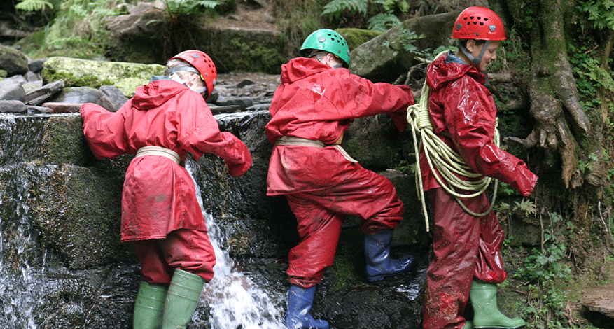 Children in Wellingtons on waterfall at Youth Adventure Trust