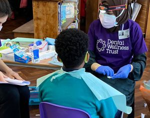 two adults and child in school Save Kids Teeth