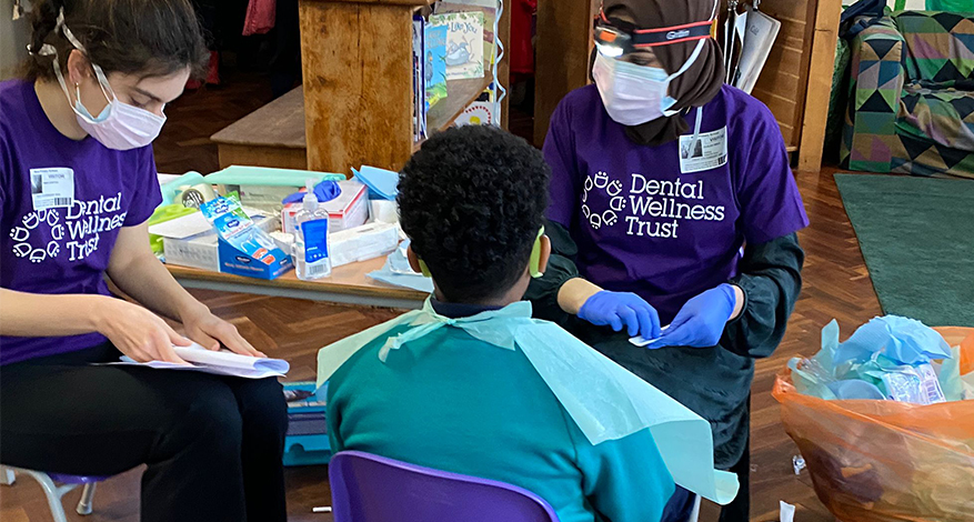 two adults and child in school Save Kids Teeth