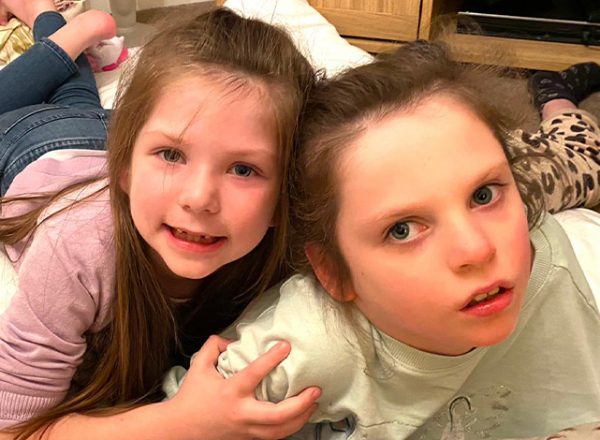 Little girl and sister lying on rug together