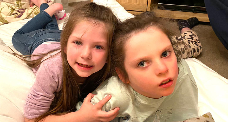 Little girl and sister lying on rug together