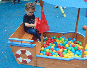 child playing with coloured balls in model boat