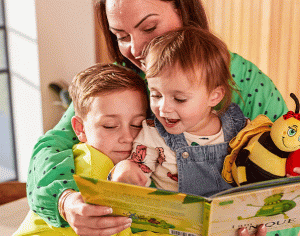 Woman reading to two infants from a book