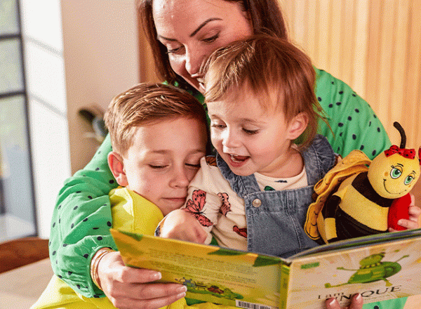 Woman reading to two infants from a book
