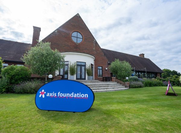 An Axis Foundation logo banner in front of the London Golf Club's clubhouse.