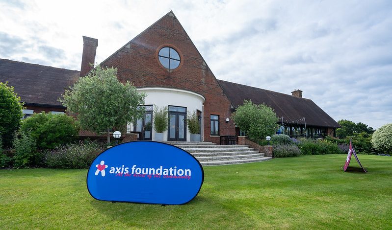 An Axis Foundation logo banner in front of the London Golf Club's clubhouse.