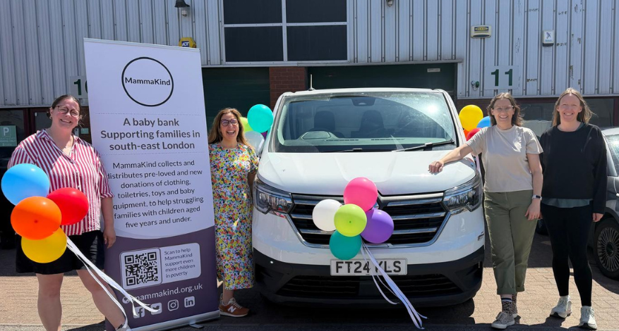 white van centre with three people and balloons plus large sign